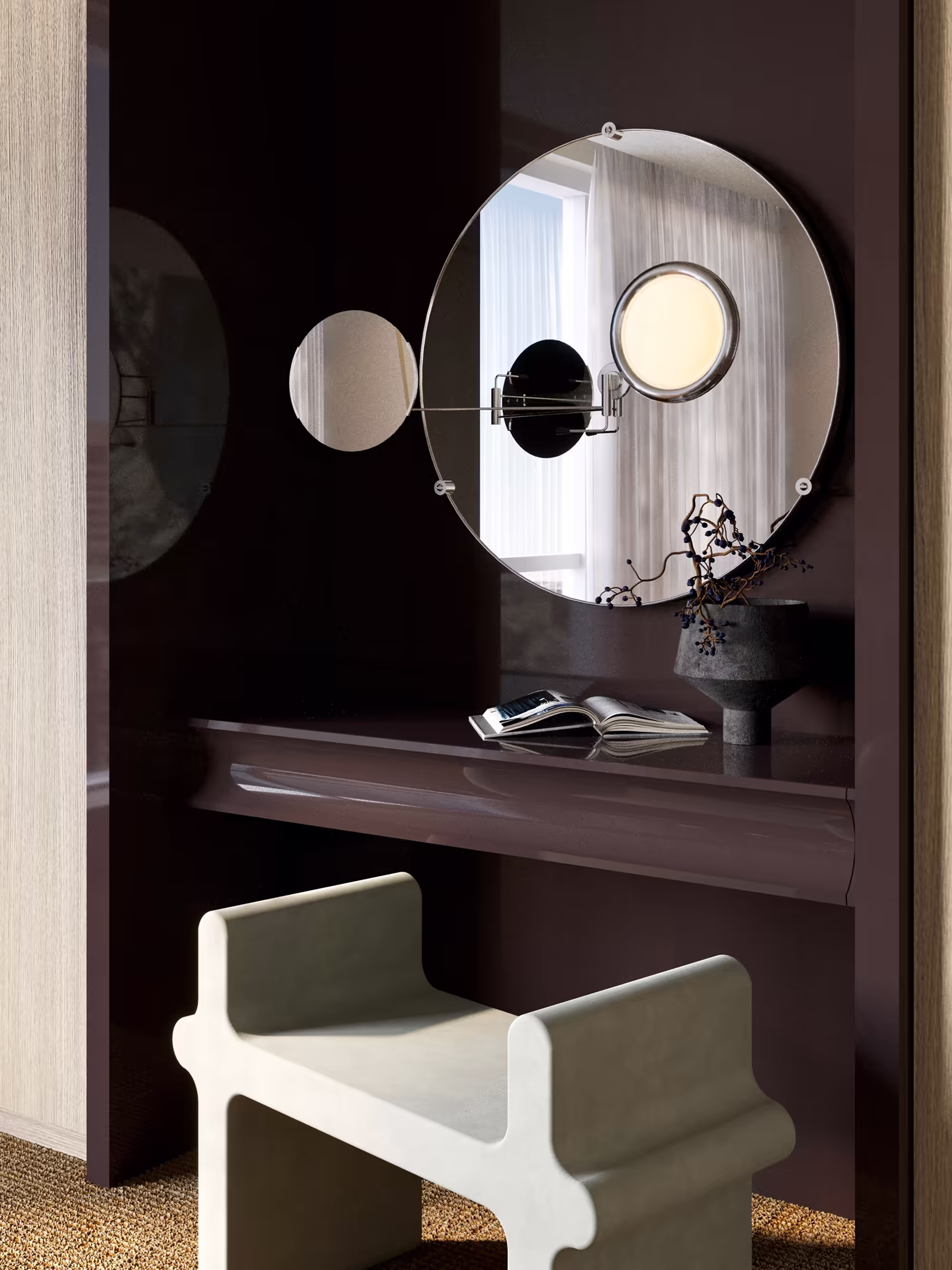 Close-up of a bespoke vanity area with a high-gloss backdrop and Eileen Grey Satellite mirror. A sculptural stool by Giobagnara stands in front of a sleek dark desk. Minimalist décor and soft lighting create a refined atmosphere.